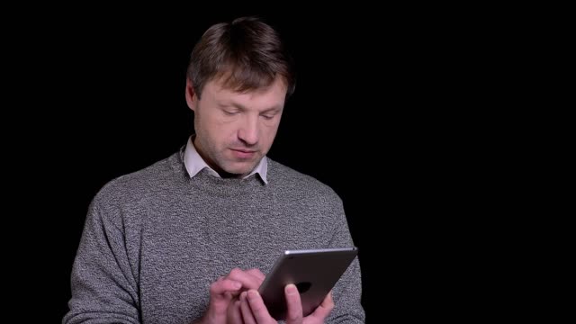 Nahaufnahme-von-erwachsenen-kaukasischen-Mann-Messaging-auf-dem-Tablet-in-der-Vorderseite-der-Kamera-mit-Backround-isoliert-auf-schwarz