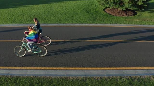 Aerial-side-view-of-young-lgbt-couple-riding-bikes