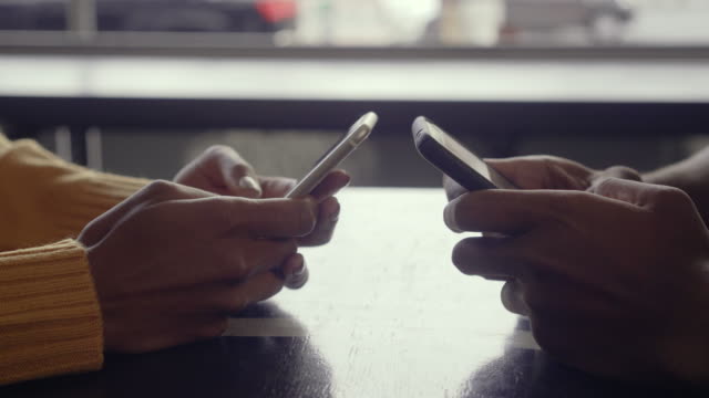 Couple-using-their-mobile-phones-in-cafe