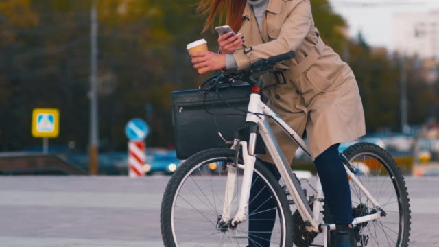 Mujer-de-negocios-consumada-en-bicicleta-con-teléfono-móvil-fuera