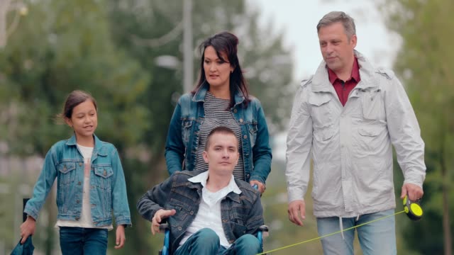 Behinderter-junger-Mann-auf-einem-Spaziergang-mit-seiner-Familie.-Portraitansicht.