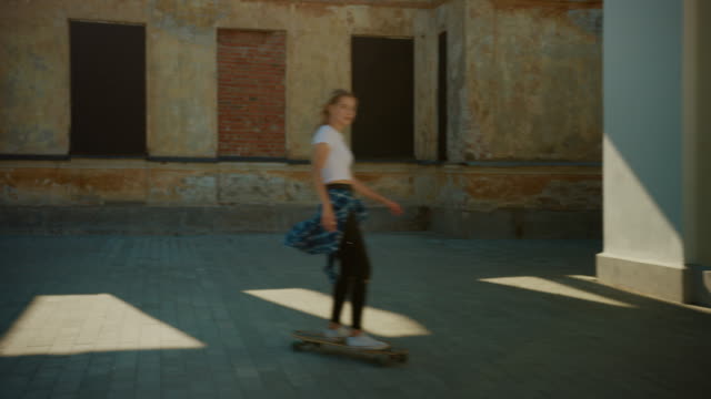 Cuatro-cool-Young-Girls-y-Guys-Riding-Longboard-y-Skateboard-a-través-de-la-elegante-parte-cultural-de-la-cadera-de-la-ciudad.-Skateboarding,-Shooting-Social-Media-Videos-on-Smartphone-in-Post-Industrial-Neighbourhood