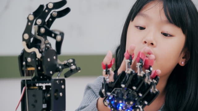 Little-Girl-is-playing-with-robotic-arm-in-a-school.-She-is-controlling-it-by-her-hand.