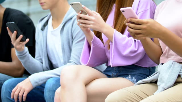Female-and-male-teens-addicted-with-smartphones,-scrolling-social-networks