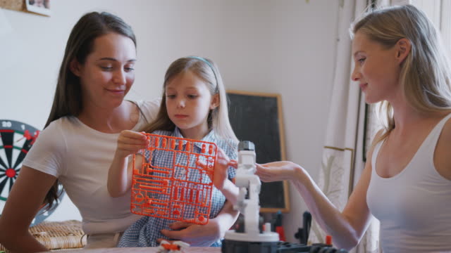 Gleich-Geschlecht-weibliche-paar-machen-Roboter-aus-Kit-mit-Tochter-zu-Hause-zusammen