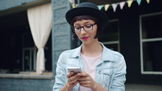 Glückliche-junge-Frau-mit-modernen-Smartphone-im-Freien-in-der-Stadt-Straße-berühren-Bildschirm
