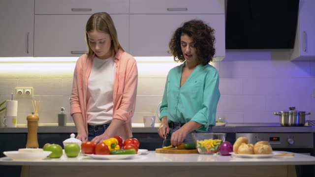 Hübsche-Frauen-kochen-zu-Hause,-Schneiden-von-frischem-Gemüse-auf-Küchentisch,-Gesundheit