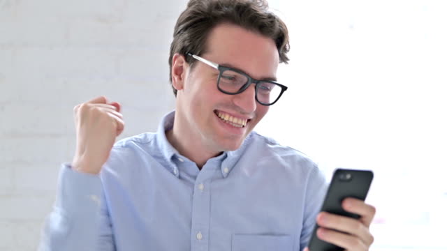 Portrait-of-Young-Man-Celebrating-Success-on-Smartphone