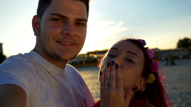 Beautiful-lovers-on-video-calling-their-friends-from-beach-at-sunset