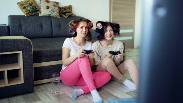 Zwei-lustige-Frauen-spielen-Konsolenspiele-mit-Gamepad-und-haben-Spaß-zu-Hause