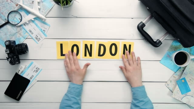 Draufsicht-Zeitraffer-Hände-auflegen-weißen-Schreibtisch-Wort,-das-"LONDON"-mit-Reisen-Gegenständen-dekoriert