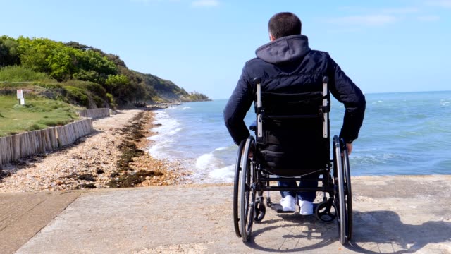 La-parte-trasera-del-hombre-discapacitado-en-silla-de-ruedas-en-la-playa