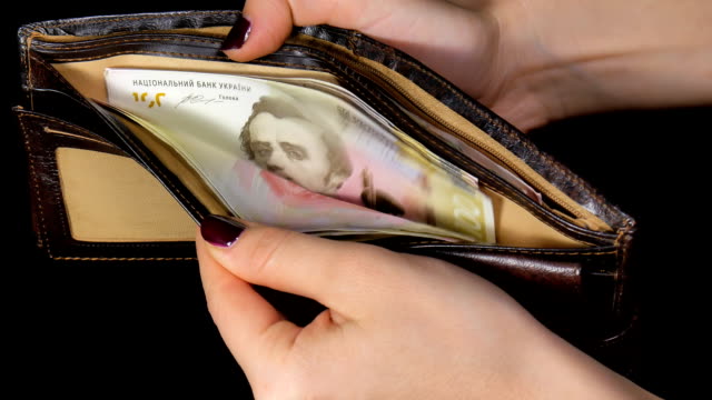 Female-hands-out-cash-dollars-from-purse.-Dollar-and-hryvnia.-Black-background.