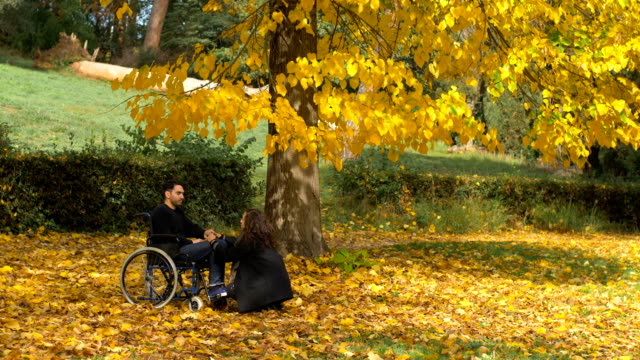 Mann-im-Rollstuhl-mit-seiner-Freundin-im-Park-im-Herbst