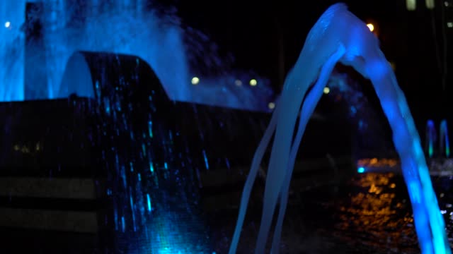 Colorful-streams-of-water-in-fountain-at-night-time,-super-slow-motion.