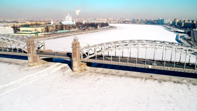 Aerial-Flight-over-snowy-river-with-bridge-in-Saint-Petersburg-city,-Russia