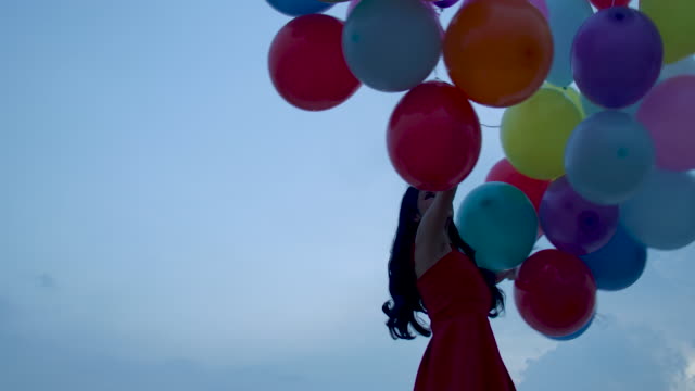 Girl-holding-balloon-with-sky-background-in-slow-motion.