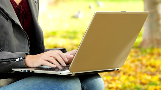 Manos-de-mujer-escribiendo-en-un-ordenador-portátil-en-un-parque