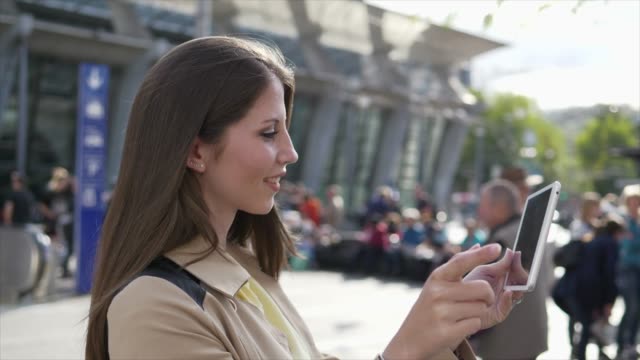 Gut-aussehende-junge-Frau,-die-auf-digitale-Tablet-im-öffentlichen-Raum-außerhalb-arbeiten