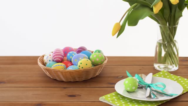 easter-eggs-in-basket-and-flowers-on-served-table