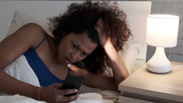 Eine-schwarze-Frau-SMS-auf-Handy-im-Bett