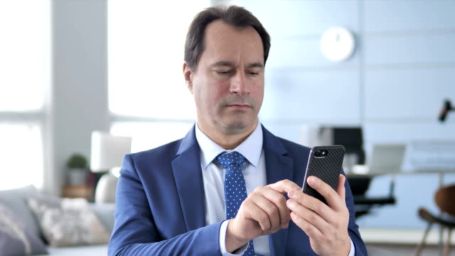 Middle-Aged-Businessman-Using-Smartphone,-Typing-Message