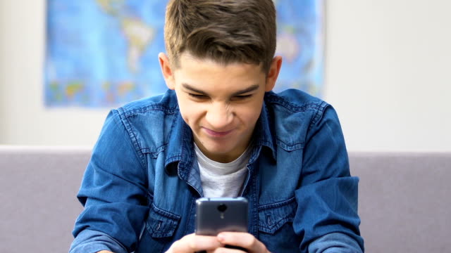 Stressed-school-boy-finally-winning-in-video-game-on-smartphone,-leisure-time
