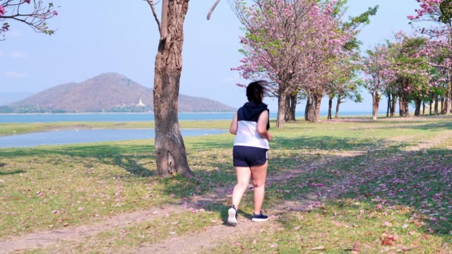 Una-mujer-asiática-gorda-que-trota-en-la-luz-del-sol-natural-por-la-mañana.
Ella-está-tratando-de-perder-peso-con-el-ejercicio.--concepto-de-salud-con-ejercicio.-Cámara-lenta