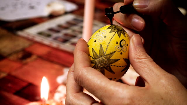 manos-de-artesano-femenino-pintando-el-proceso-folclórico-de-huevo-de-Pascua-creando-capa-por-capa-con-la-cera-y-usando-pinturas-multicolor-de-cerca