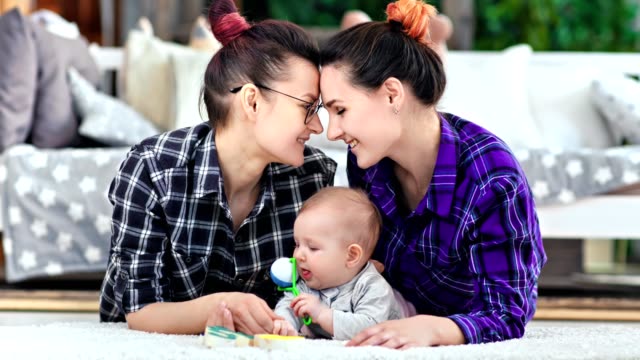 Female-couple-feeling-love-having-tenderness-together-posing-with-cute-child-at-home