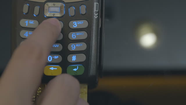 Credit-card-machine-chip-and-pin-code-being-entered-by-a-man-POV.-A-detail-zoomed-in-of-the-hand-with-no-faces-shown.-In-4K,-real-time.-Credit-or-debit-card-being-used-for-consumer-spending.