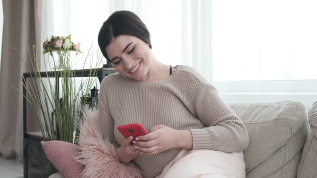 Woman-using-mobile-phone-on-sofa-at-home