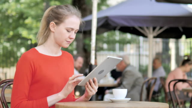 Mujer-joven-usando-la-tableta,-sentado-en-Cafe-Terrace