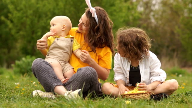 Lovely-family-hugging-in-the-park-at-a-picnic.-Happy-Easter-family.-Mom-and-two-sons.-Mothers-Day