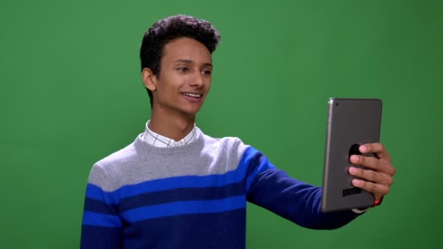 Closeup-shoot-of-young-attractive-indian-male-having-a-video-call-on-the-tablet-with-background-isolated-on-green