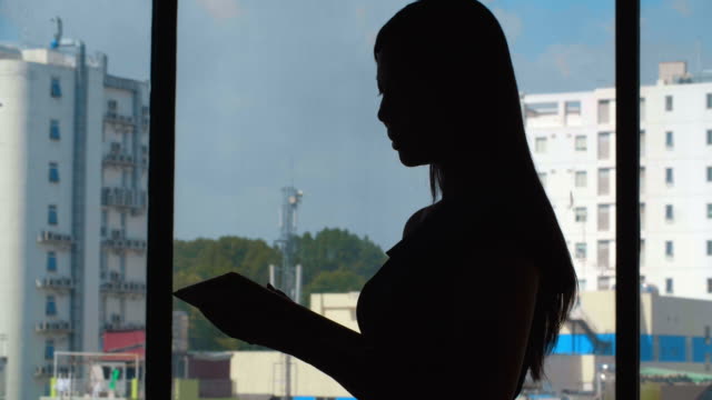 Mujer-usando-la-tableta-en-la-ventana