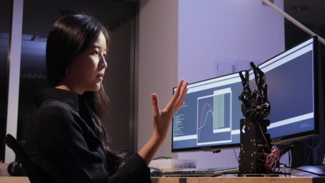 Pruebas-asiáticas-de-mano-cyborg-en-la-sala-de-control.-Mujer-haciendo-su-proyecto-robot-que-prueba-la-señal-del-sensor.-Concepto-de-tecnología-e-innovación.