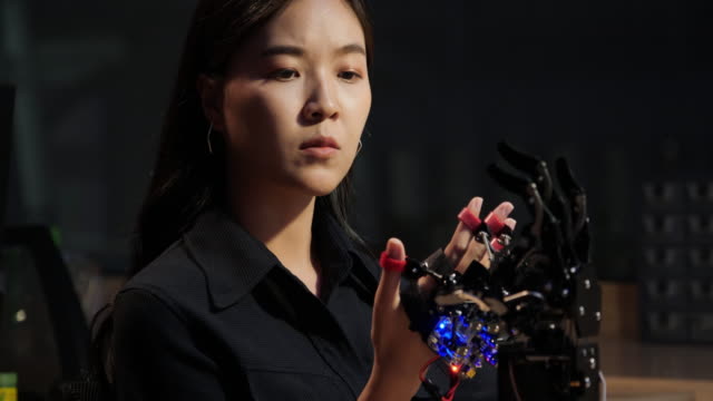 Asiatische-Tests-Cyborg-Hand-im-Kontrollraum.-Weiblich,-die-ihr-Roboterprojekt-macht,-testet-sensorsignal.-Technologie--und-Innovationskonzept.
