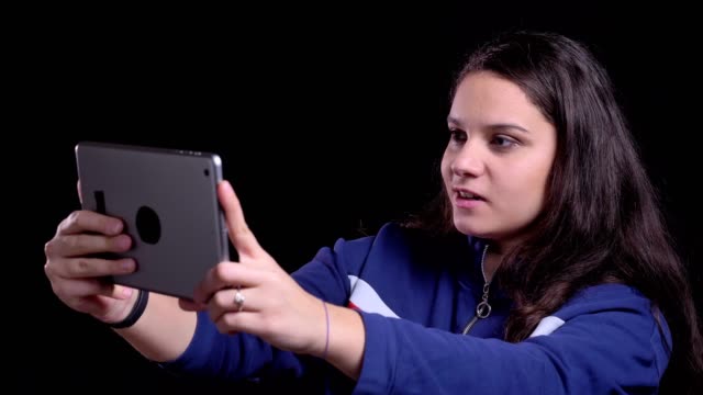 Nahaufnahme-Porträt-von-erwachsenen-attraktiven-kaukasischen-Frau-mit-einem-Videoanruf-auf-dem-Tablet-mit-Hintergrund-isoliert-auf-schwarz