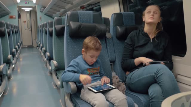 Familia-viajando-en-tren-y-entretenido-con-electrónica