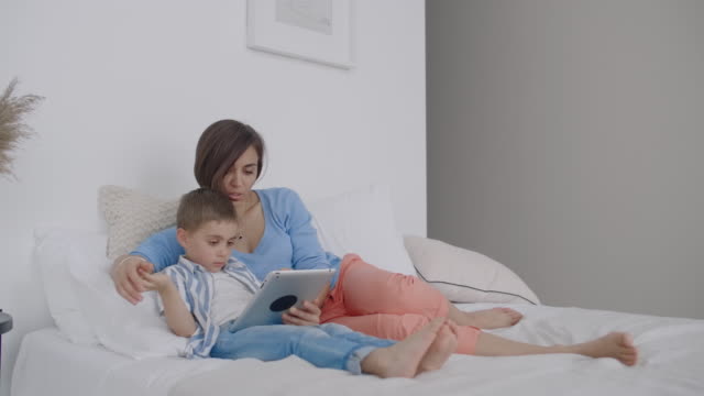 Happy-family-mother-and-child-son-with-tablet-in-evening.-Happy-family-mother-and-child-son-with-tablet-in-evening-before-bed.