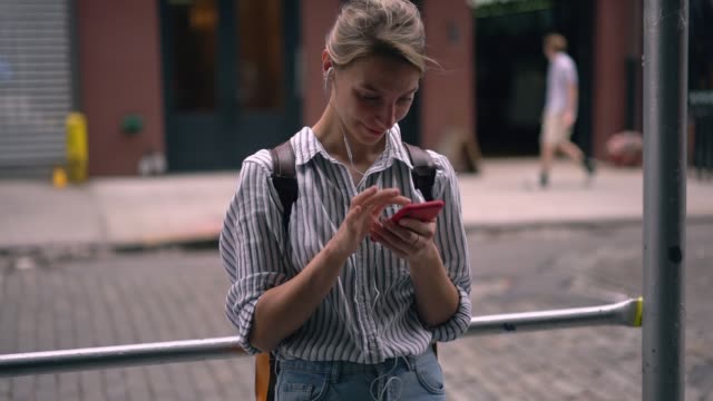 Slow-motion-effect-of-hipster-girl-with-smartphone-device-in-hand-listening-audio-record-from-webinar-connected-to-4g-wireless