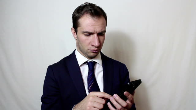 Young-handsome-businessman-is-viewing-a-news-feed-on-his-smartphone.