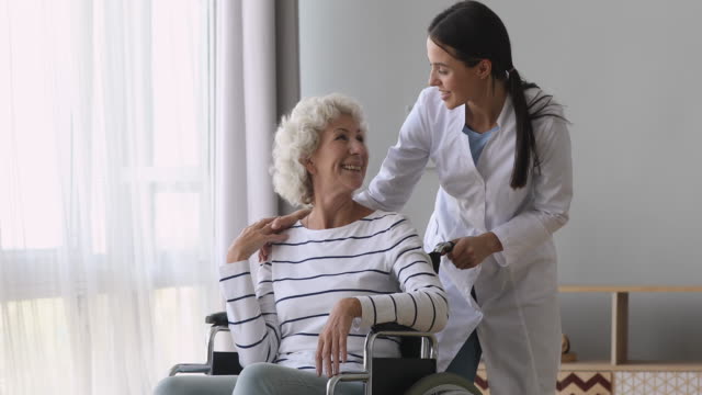 Junge-Frau-Krankenschwester-Betreuer-sprechen-helfen-Senior-Großmutter-auf-Rollstuhl