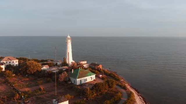 Lighthouse-on-the-cape.-beautiful-shot-from-the-air,-flying-over-the-lighthouse-during-sunset,-beautiful-light,-scenic-landscape-sky-and-sea,-Suristic-colors.-Flying-around-the-lighthouse
