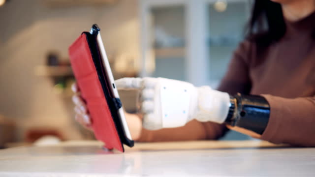 Person-types-on-a-tablet-with-bionic-hand,-close-up.