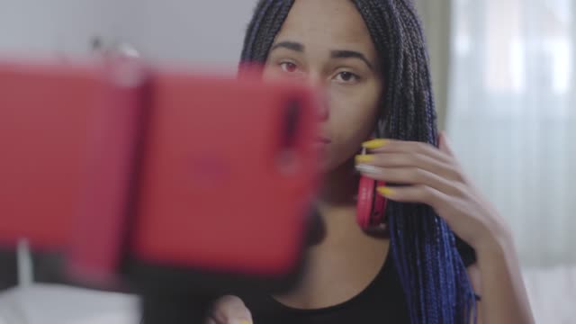 Primer-plano-de-la-chica-afroamericana-mirando-la-pantalla-del-teléfono-inteligente-y-hablando.-Videoblog-de-grabación-de-adolescentes-positivo.-Estilo-de-vida-moderno,-tecnologías-inalámbricas,-redes-sociales.