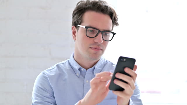 Portrait-of-Relaxed-Young-Man-using-Smartphone
