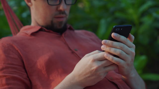 man-is-typing-at-smartphone-in-garden