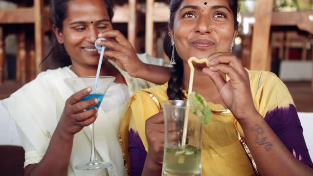 Two-women-chilling-sipping-drinks-using-technology-in-cafe